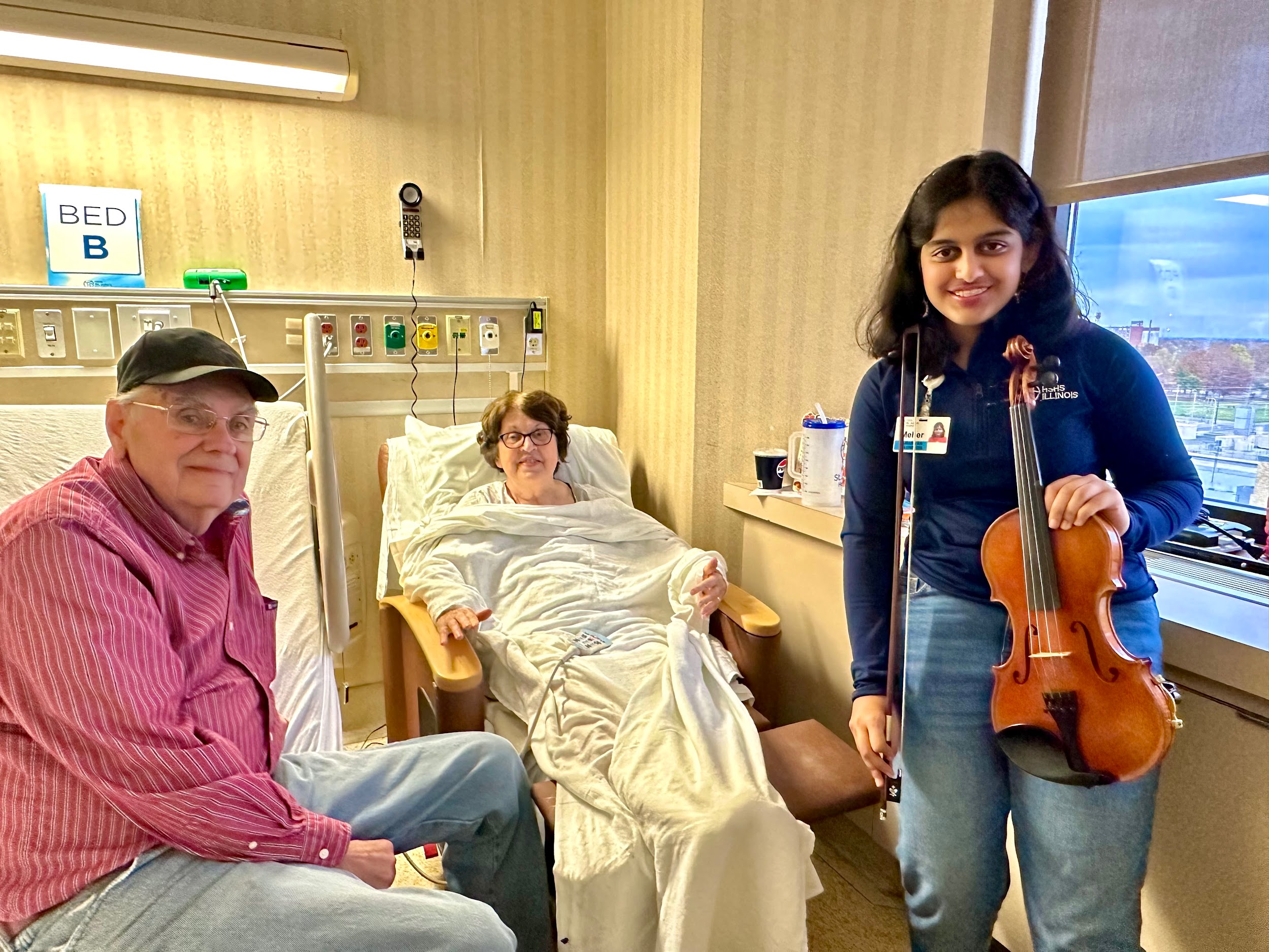 Meher Garg with her violin next to two elders